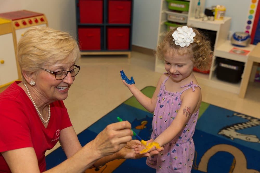 A teacher and a young girl finger painting together